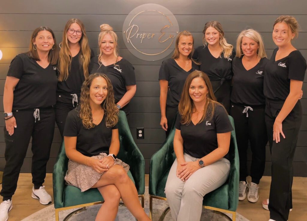 women standing in front of their logo for staff picture